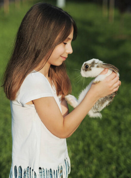 The girl hugs a little cute rabbit. Rabbit symbol of Easter. Friendship between child and animal concept.