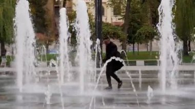 Neşeli, kaygısız Afrikalı eğleniyor ve dans ediyor. Afrika dansı kamera önünde. Pozitif Afro-Amerikan adam dans ediyor. Sokakta bir Afrikalı dans ediyor. Çeşmede dans et. 4K 'da çekilmiş.