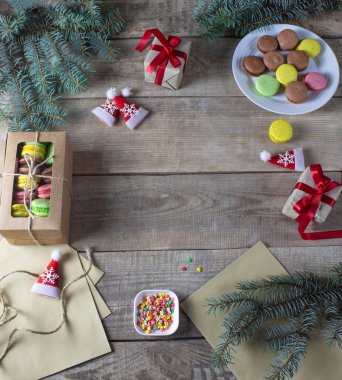 Renkli Fransız kurabiyeleri. Ahşap arka planda makarnalar. Noel arkaplanı. Noel ağacının dalları. Hediye. Çerçeve. Kopyalama alanı