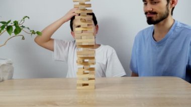 İki kişilik bir aile evlerinde ahşap bir kuleyle masa oyunu oynuyor. İki kardeş oynar ve bir tuğla çıkarır ve kule çöker. 4