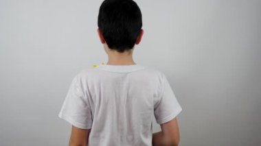 Küçük mutlu çocuk kameraya doğru bir buket çiçek tutuyor ve gülümsüyor. Gülümseyen küçük bir çocuğun portresi. Oğlan bir buket sarı lale verir. 4K