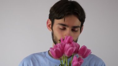 Elinde bir buket lale olan komik bir adam. Elinde çiçek tutan sakallı adam. İki buket çiçek. Sevgililer Günü. Kadınlar Günü. Bahar tatili. Neşeli duygular. 4K