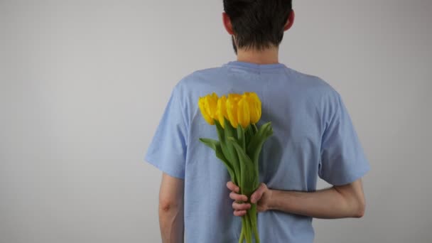 素敵な男はカメラと笑顔に花の花束を保持しています その少年は黄色いチューリップの花束をあげます — ストック動画