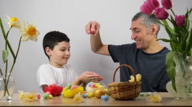 Aileyi Paskalya 'ya hazırlıyorum. Baba ve oğlu Paskalya yumurtalarını boyuyor. Gülen yüzler. Mutlu aile yumurta çizer. 4K
