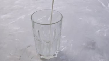 Süt gri arka planda bir süt bardağına dökülür. Protein. 4K