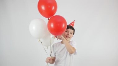  Kırmızı bir doğum günü şapkası takan yakışıklı bir çocuğun portresi. Kırmızı ve beyaz toplar. 4K