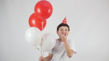 Doğum günü. Balonlar. Kırmızı doğum günü şapkalı bir çocuğun portresi. Kırmızı ve beyaz toplar. 