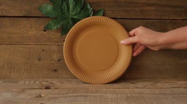 Geri dönüşüm ve çevre dostu kavram. Tahta bir arka planda kağıttan yapılmış tek kullanımlık sofra takımı. 4K