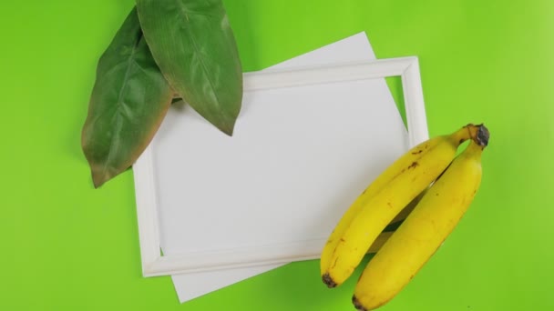 花の夏の背景 バナナと緑の葉は白い紙に文字で書かれている 上からの眺め — ストック動画