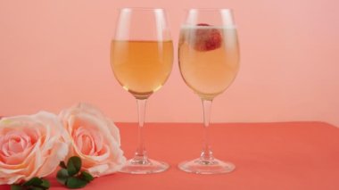 Pembe arka planda pembe güllerin yanında iki bardak şampanya var. Romantizm, aşk. Kutlama, sevgililer günü, doğum günü. 4K