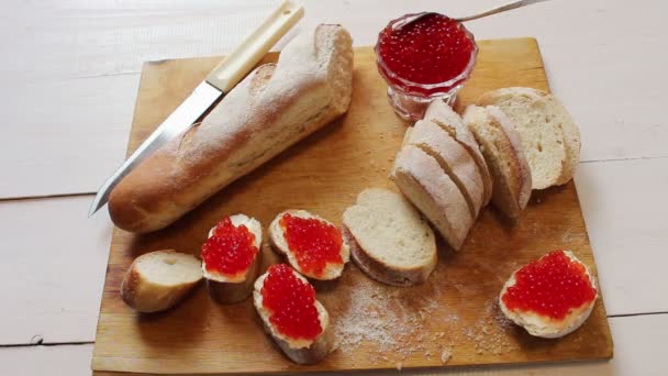 Röd kaviar. Fransk baguette skivad och röd kaviar på en butyrboard — Stockvideo