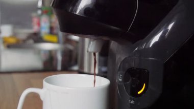 Makineden beyaz fincana taze kahve dökülüyor.