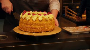 Pasta şefi pasta tezgahında kremayla süsleme yapıyor.