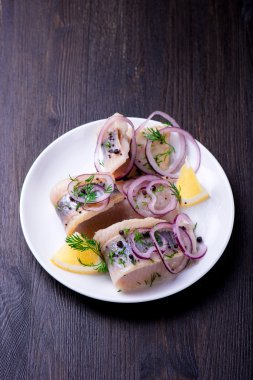 Biber, otlar, tuz ve limon üzerinde beyaz seramik plat ile ringa balığı