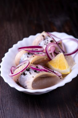 Biber, otlar, tuz ve limon üzerinde beyaz seramik plat ile ringa balığı