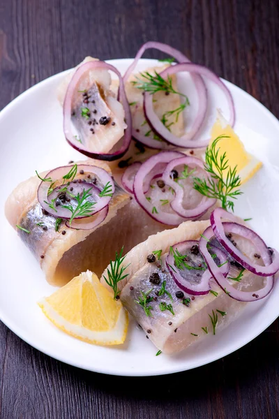 Biber, otlar, tuz ve limon üzerinde beyaz seramik plat ile ringa balığı — Stok fotoğraf