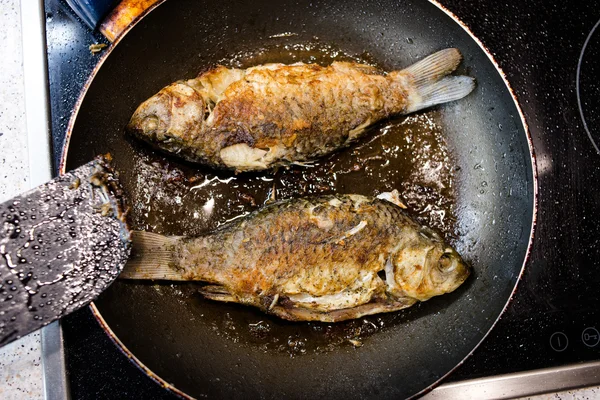 Peixe frito em uma frigideira no fogão — Fotografia de Stock