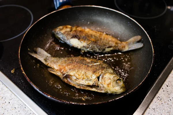 Peixe frito em uma frigideira no fogão — Fotografia de Stock