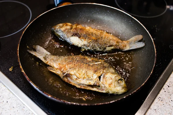 Peixe frito em uma frigideira no fogão — Fotografia de Stock