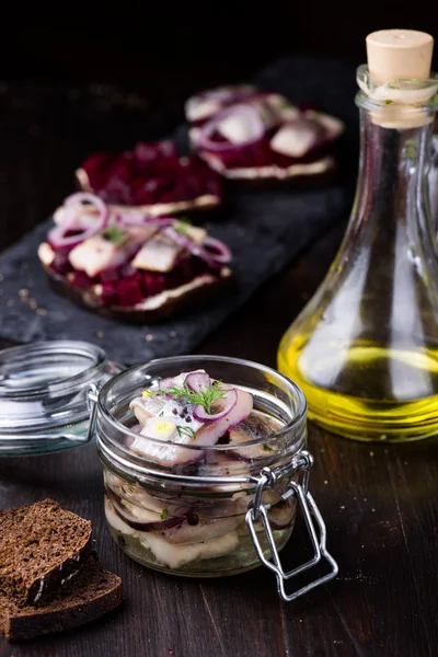 Marinated herring in a jar with herbs and onion Royalty Free Stock Photos