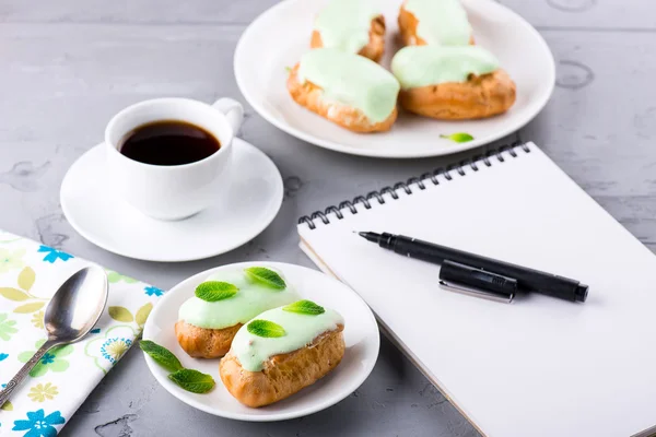 Fazendo sua lista enquanto toma uma xícara de café com eclairs — Fotografia de Stock