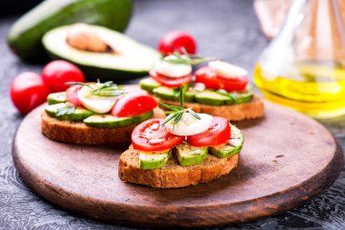 Çavdar ekmeği, avokado, yumurta, domates ahşap tahta üzerinde sandviç