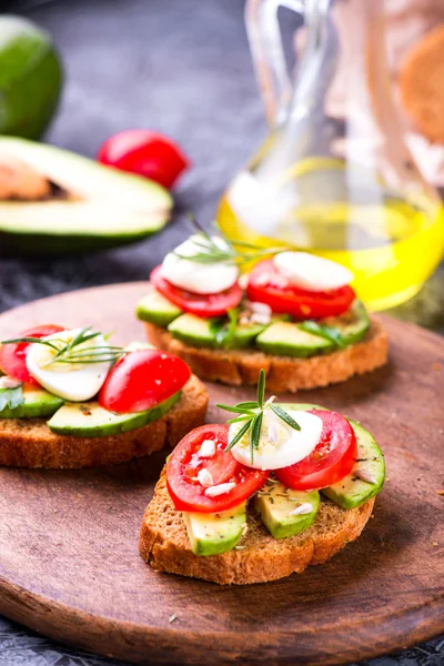 Sandwich con pan de centeno, aguacate, huevo, tomate sobre tabla de madera — Foto de Stock