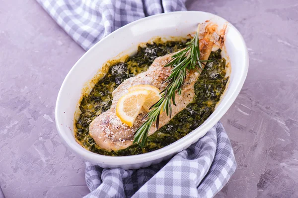 Cooked white fish fillet with herbs on fried spinach in baking d — Stock Photo, Image