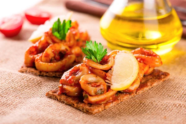 Appetizer with spicy tomato squids and lemon on toast — Stock Photo, Image