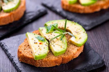 Avokado ile tost, kayrak tahta üzerinde otlar