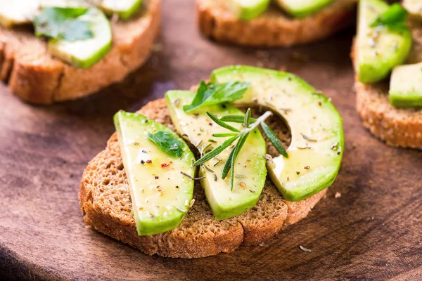 Toast with avocado, herbs on wooden board — Stock Photo, Image