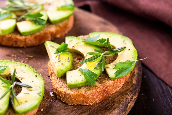 Toast with avocado, herbs on wooden board — Stock Photo, Image