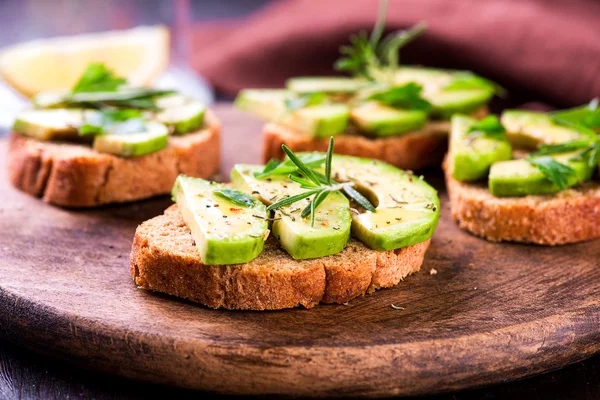 Toast with avocado, herbs on wooden board — Stock Photo, Image