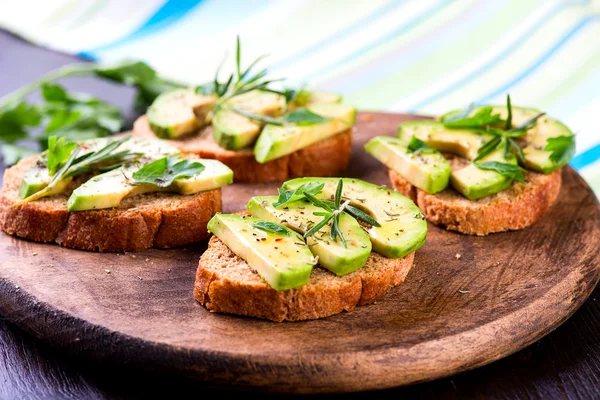 Toast with avocado, herbs on wooden board — Stock Photo, Image