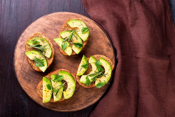 Tostadas con aguacate, hierbas sobre tabla de madera — Foto de Stock