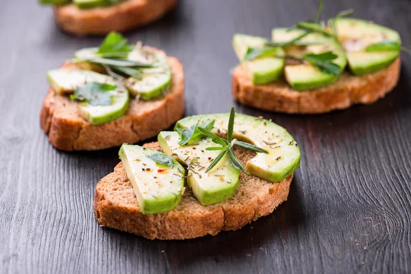 Toast with avocado, herbs on wooden board — Stock Photo, Image