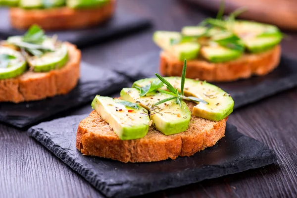 Toast med avokado, örter skiffer ombord — Stockfoto