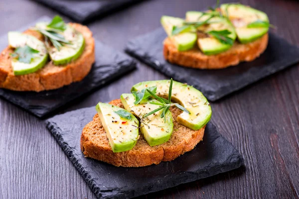 Toast med avokado, örter skiffer ombord — Stockfoto