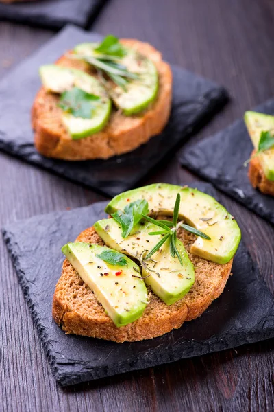 Tostadas con aguacate, hierbas en pizarra — Foto de Stock