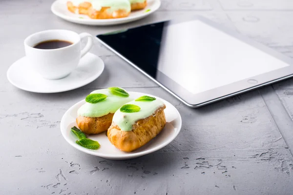 Eclares de hortelã em um prato, café e tablet digital — Fotografia de Stock