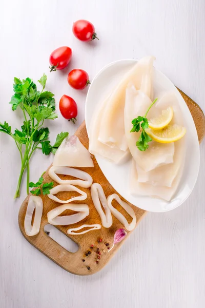 Calamar crudo e ingredientes en el plato blanco Imagen de archivo