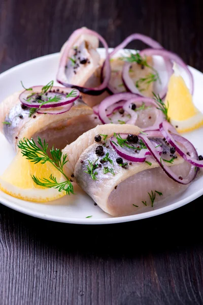 Herring with pepper, herbs, salt and lemon on white ceramic plat — Stock Photo, Image