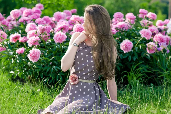 Bella giovane donna nel parco vicino peonie — Foto Stock