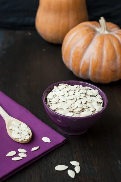 Bowl with toasted pumpkin seeds and pumpkins — Stock Photo, Image