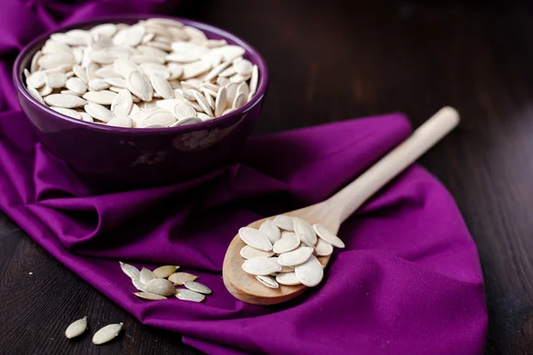 A bowl with toasted pumpkin seeds and wooden spoon — Stock Photo, Image