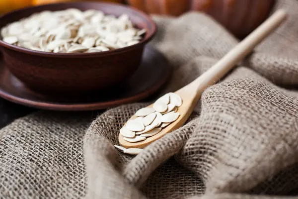 Bowl with toasted pumpkin seeds and wooden spoon — Stock Photo, Image