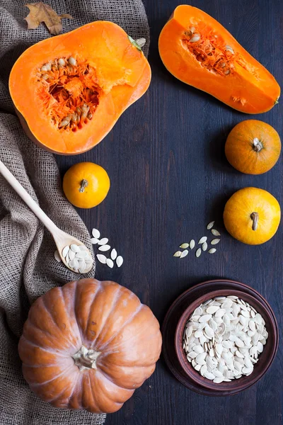 Pumpkins and a bowl with toasted pumpkin seeds, wooden spoon — Stock Photo, Image