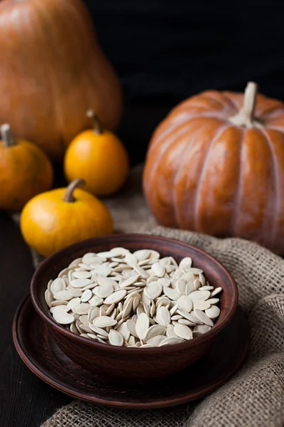 Bowl with toasted pumpkin seeds and wooden spoon — Stock Photo, Image