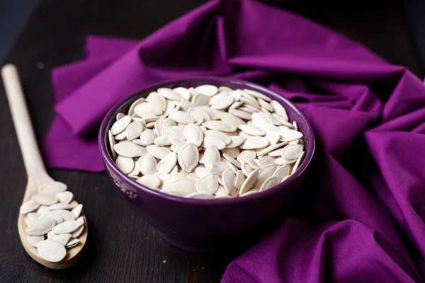 A bowl with toasted pumpkin seeds and wooden spoon — Stock Photo, Image