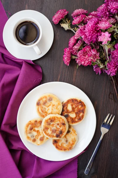 Heerlijke huisgemaakte kaas pannenkoeken met zwarte koffie — Stockfoto